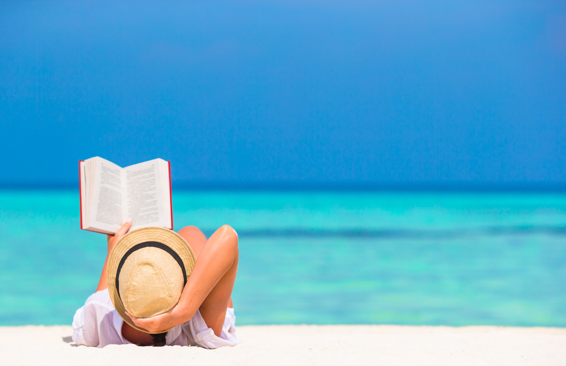 Young woman reading book during tropical white beach - Study Breaks