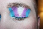 Photo of a trans person with eyeshadow that is the color of the transgender pride flag