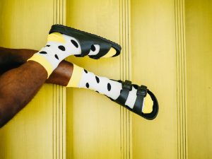 man wearing black birkenstocks with polka dot socks on a yellow background