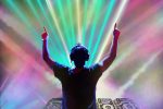 DJ performing in front of laser lights at an EDM show.