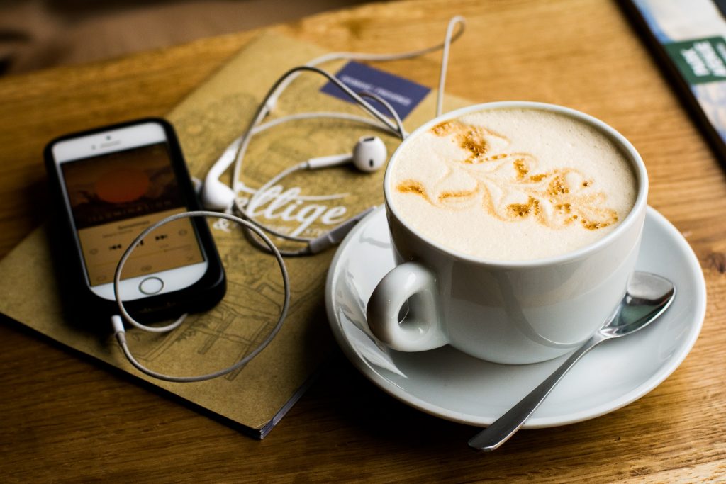 In an article about book review podcasts, a cup of coffee next to a phone with a podcast playing