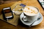 In an article about book review podcasts, a cup of coffee next to a phone with a podcast playing