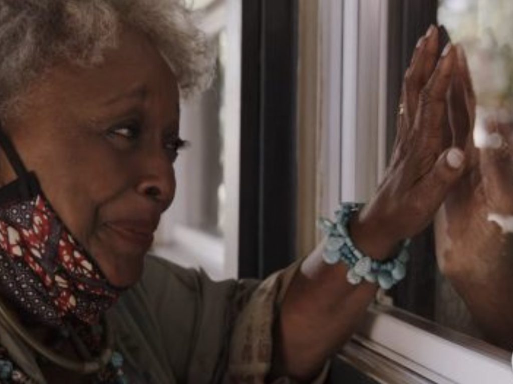 A character in Love in the Time of Corona is quarantined apart from her husband, whose hand she tries touching through glass.