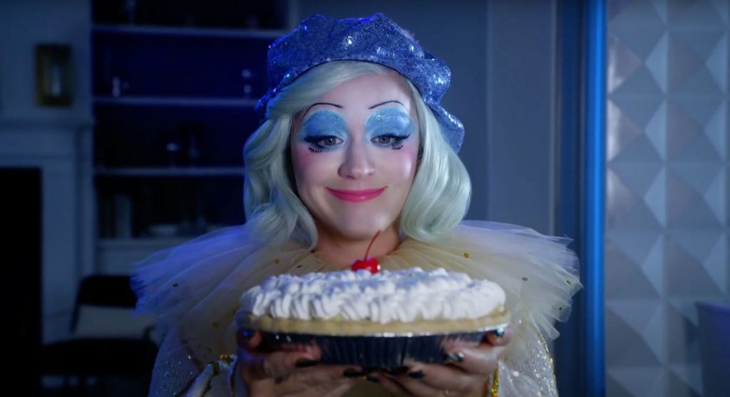 Katy Perry dressed as clown holding up a pie in the music video to her new album titled 'Smile'