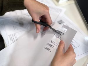 in an article about mockups, someone cutting paper with scissors