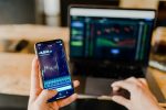in an article about crypto trading bots, a person holding a phone in front of a computer