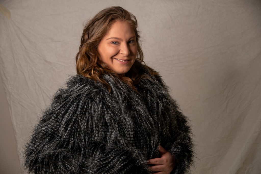 In an article about Facial Gua Sha, a person in an outfit with feathers