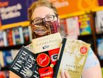 In an article about the TikTok book community, a person holding three books