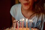 A woman blowing out birthday cake candles, for an article about birthday freebies.