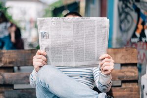 Person reading a high school newspaper on a bench.