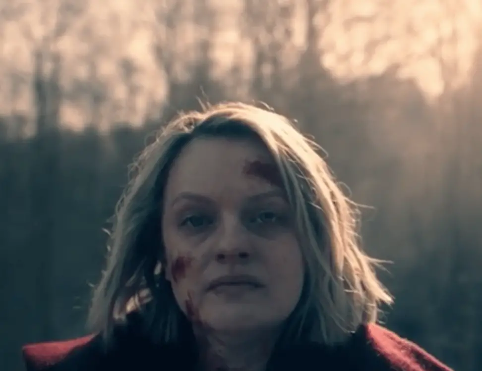 Hulu's The Handmaid's Tale protagonist, June, as she looks at the camera with a face covered in injuries from the season four finale