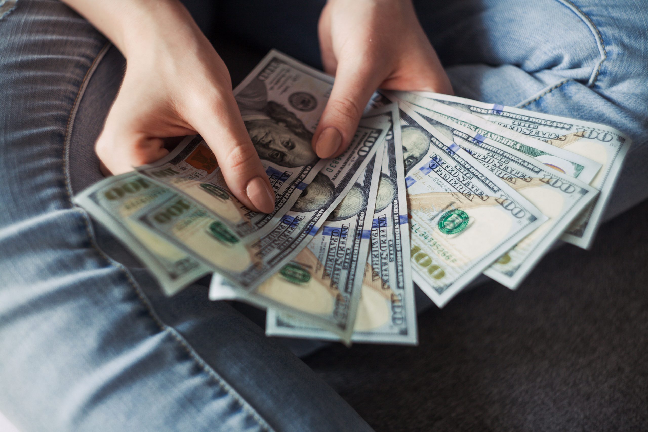 in an article about gaining extra income, a hand holding fanned out hundred-dollar bills