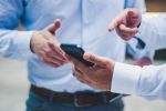 in an article about a smart app, two people pointing at a smartphone