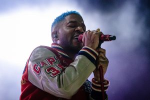 Cudi performs 'a kid named cudi' on stage while holding a mic close to his face.