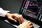 in article about novice traders, a hand on a laptop with finance charts on the screen