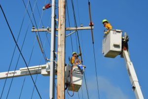 In an article about bucket bunnies, an image of two linemen maintaining powerlines