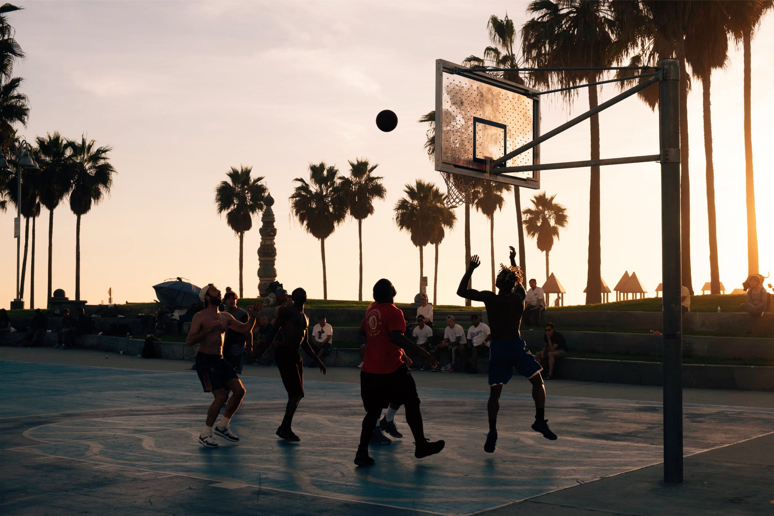 An image of people playing intramural sports shows a group throwing a basketball at sunset.