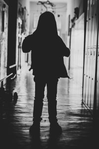 In an article about corporal punishment, a young boy's silhouette stands in an empty hallway