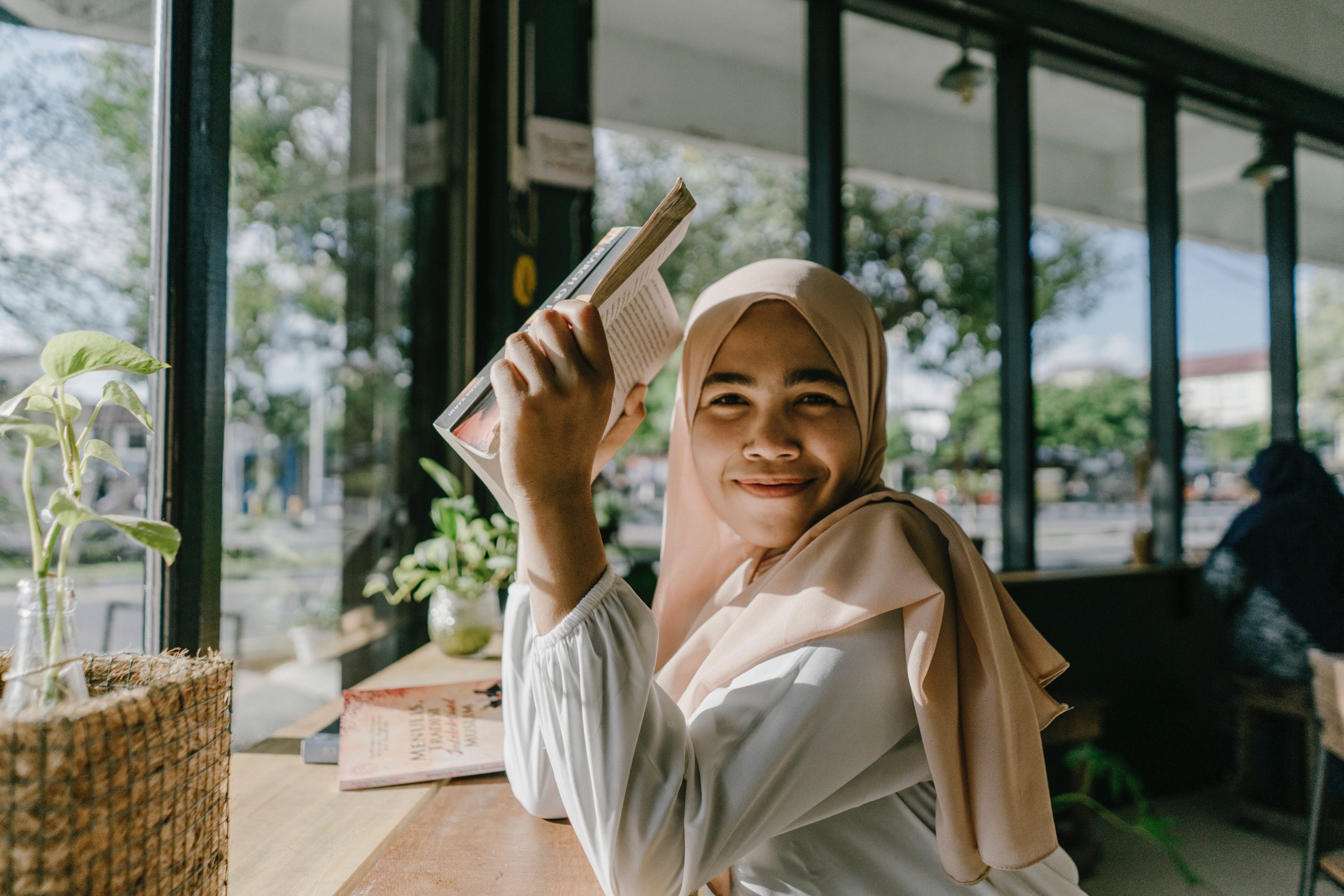 In an article on young muslims in books, an image shows a muslim woman reading in a coffee shop