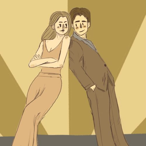 a couple standing against a wall and smiling at each other