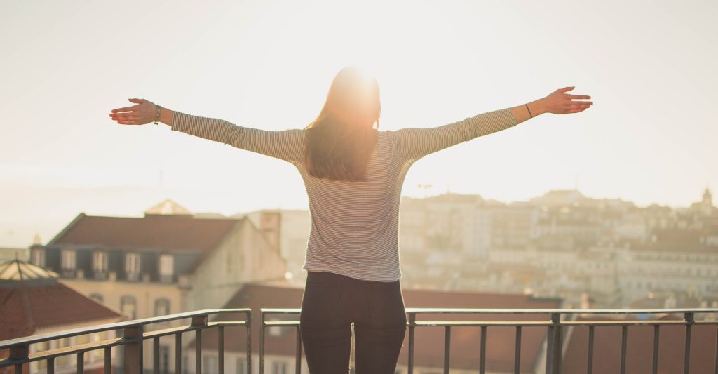 Woman standing on balcony in the sunlight absorbing vitamin D
