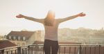 Woman standing on balcony in the sunlight absorbing vitamin D