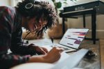 in article about bopdrop, woman laying on the ground writing in notebook while listening to music