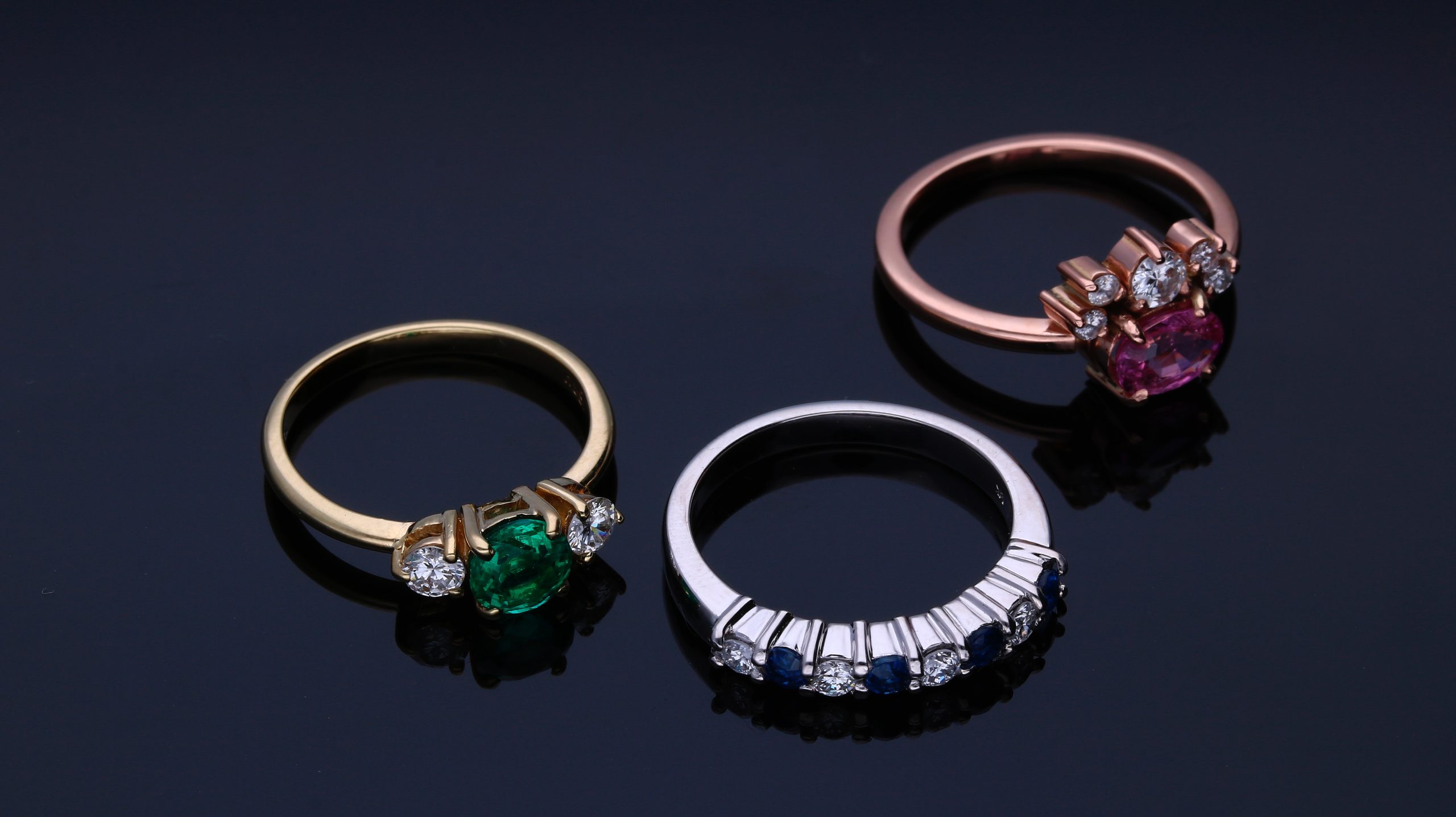 three bejeweled rings on a black backdrop