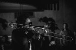 in article about kamasi washington, black-and-white image of a man playing the trombone