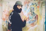 In an article about humanities degrees, an artist stands next to his canvas