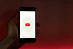 In an article about Youtube, a hand holds up a phone displaying the Youtube logo.