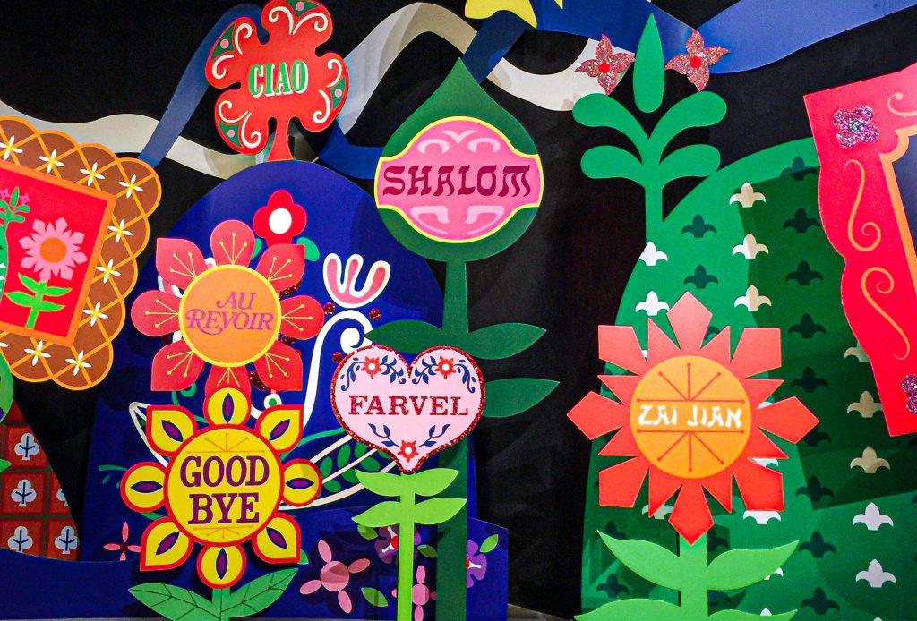 In an article about words in other languages that have no direct english translations, a field of paper flowers emblazoned with the word 'goodbye' in various languages sits against a black background.