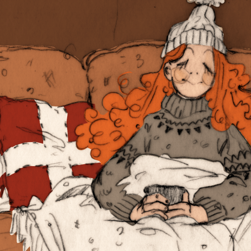 In an article about Hygge, a girl with long red hair sits on a couch with a mug of cocoa.