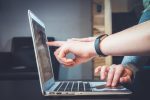 In an article about downloading videos with DRM protection, a person points to a laptop screen.