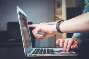 In an article about downloading videos with DRM protection, a person points to a laptop screen.