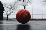 In an article about corruption in the Alabama basketball team, a basketball sits on a damp basketball court.