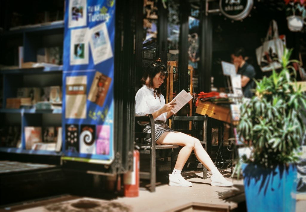 A photograph of a young woman sitting and reading a book.