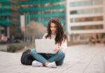 In an article about essay writing woman sitting crosslegged on sidewalk.