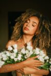 In a story about plastic surgery woman holding flowers over her chest.