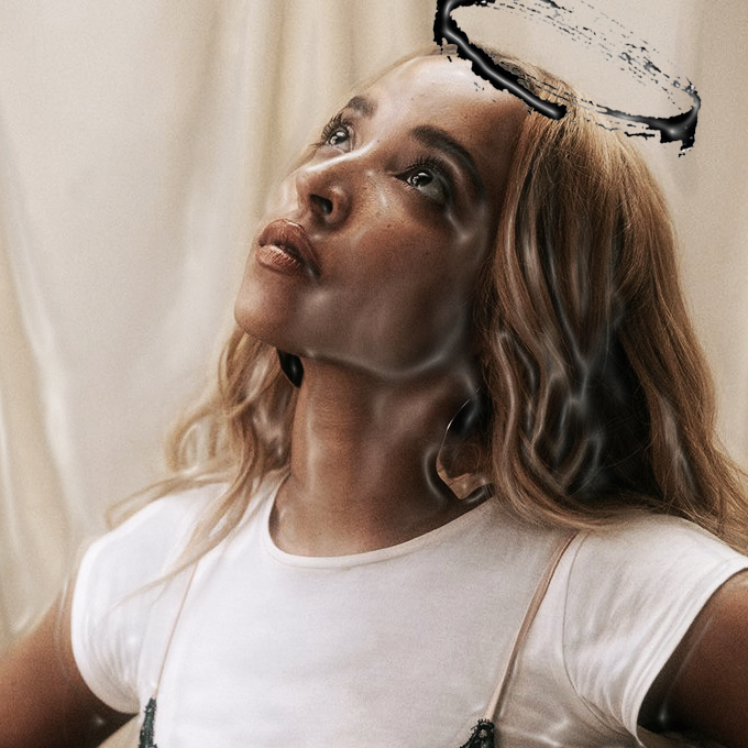 In an article about Tinashe's new album 'BB/Angel,' a woman with blonde hair looks up. She wears a white tee shirt with a slip dress over it. A hand-drawn angel halo is above her head.
