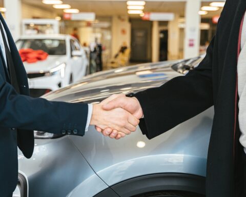 Shaking hands in front of a car